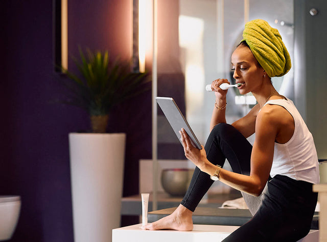 Woman brushing her teeth at the bathroom mirror
