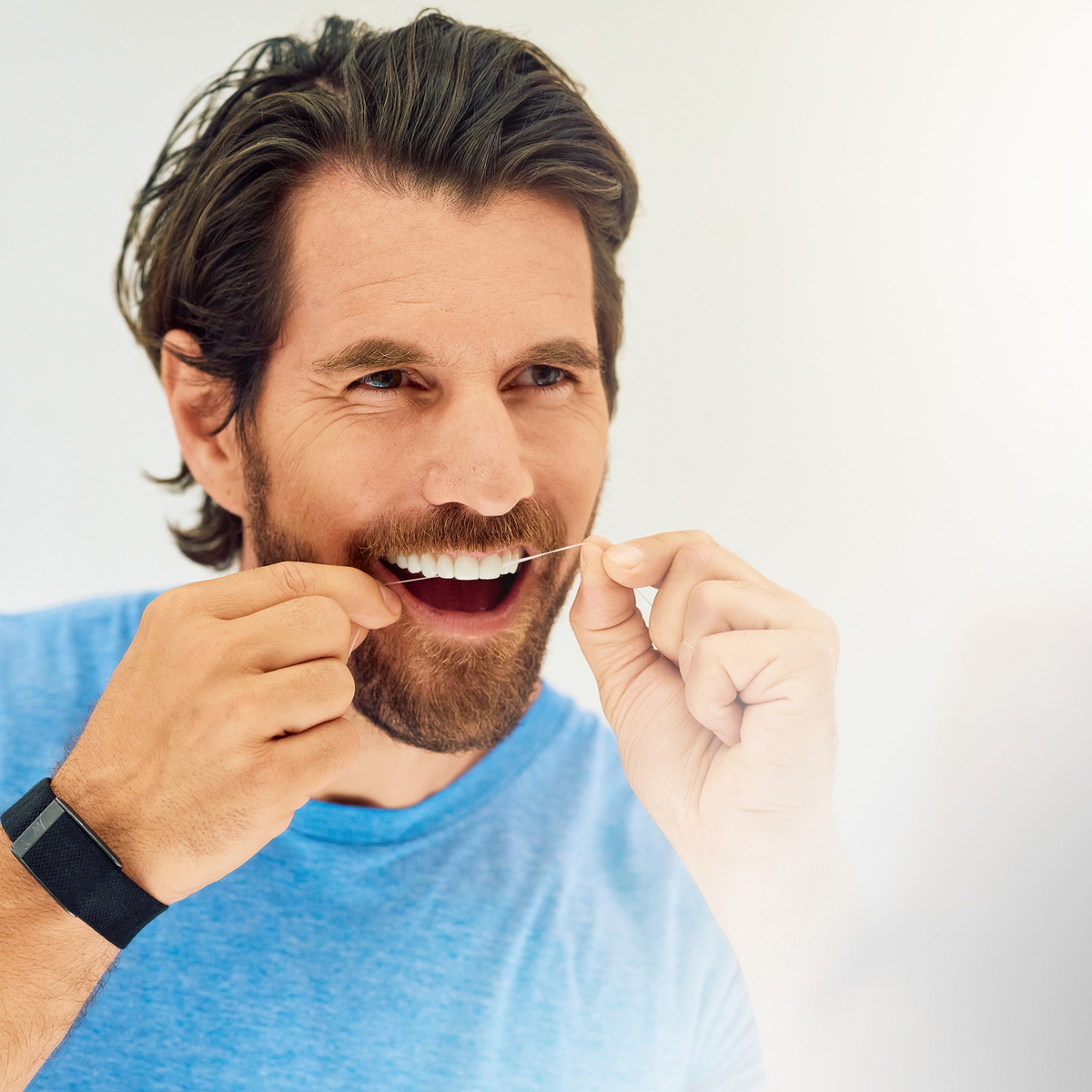 Man flossing his teeth with ApaCare Mineral Floss
