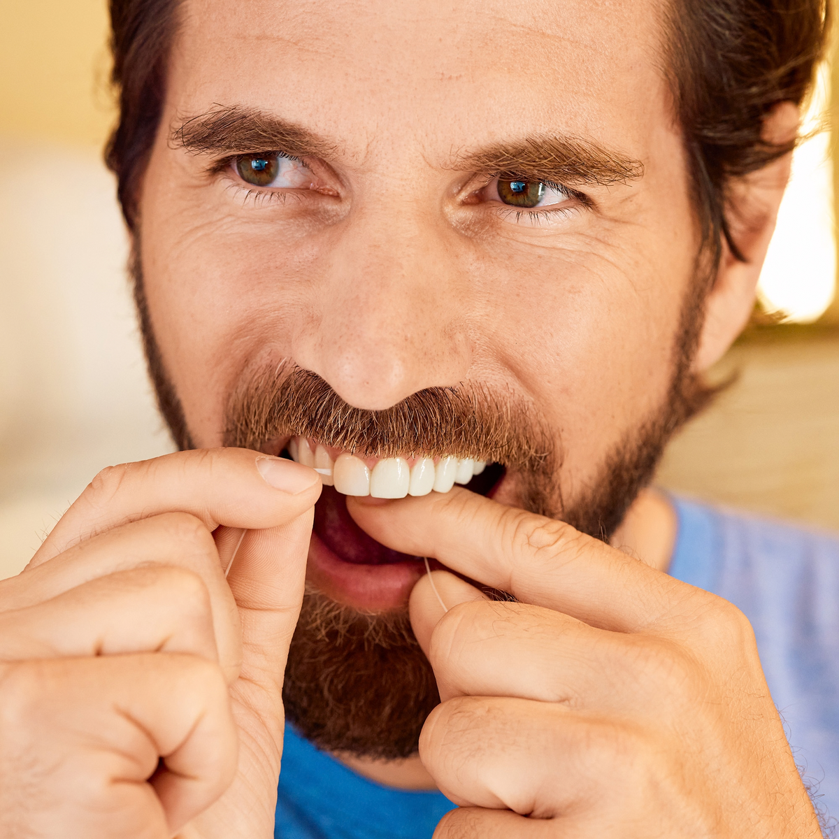 Close-up of a man flossing between his front teeth