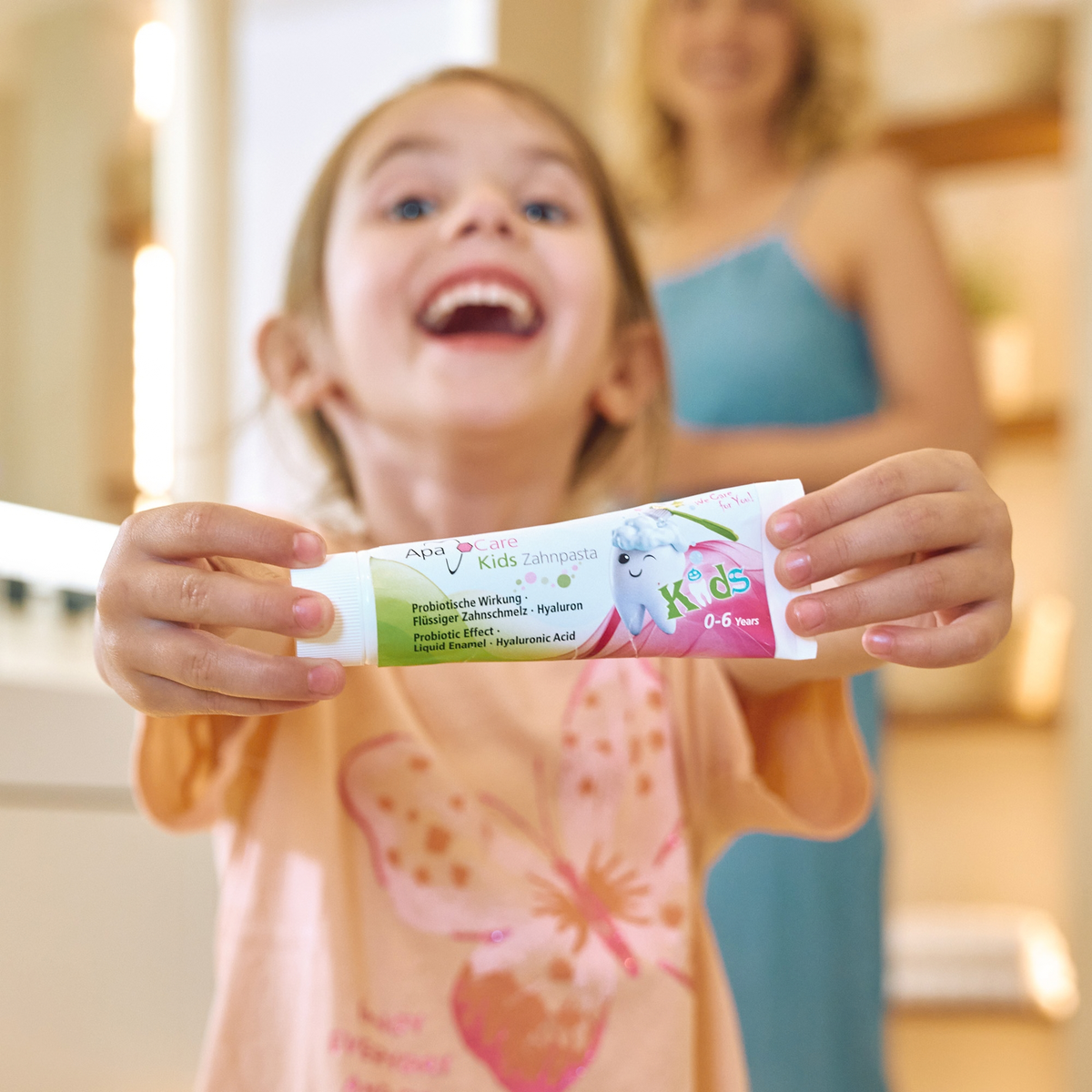 Happy girl holding a tube of ApaCare Kids Toothpaste
