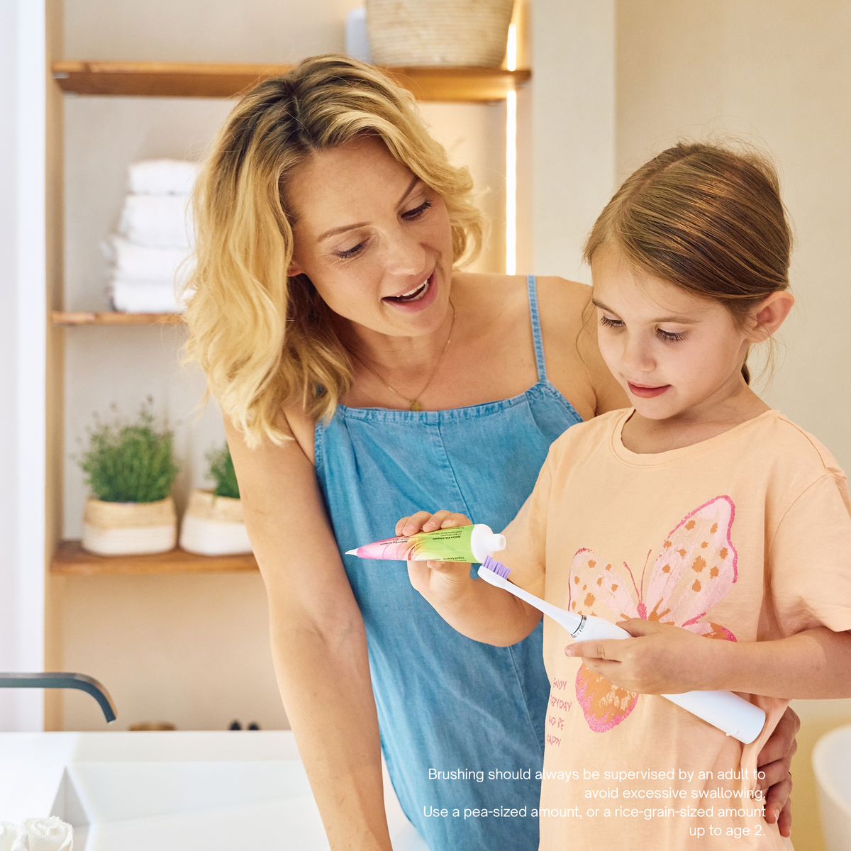 Mum helping her daughter put ApaCare Kids Toothpaste on a toothbrush
